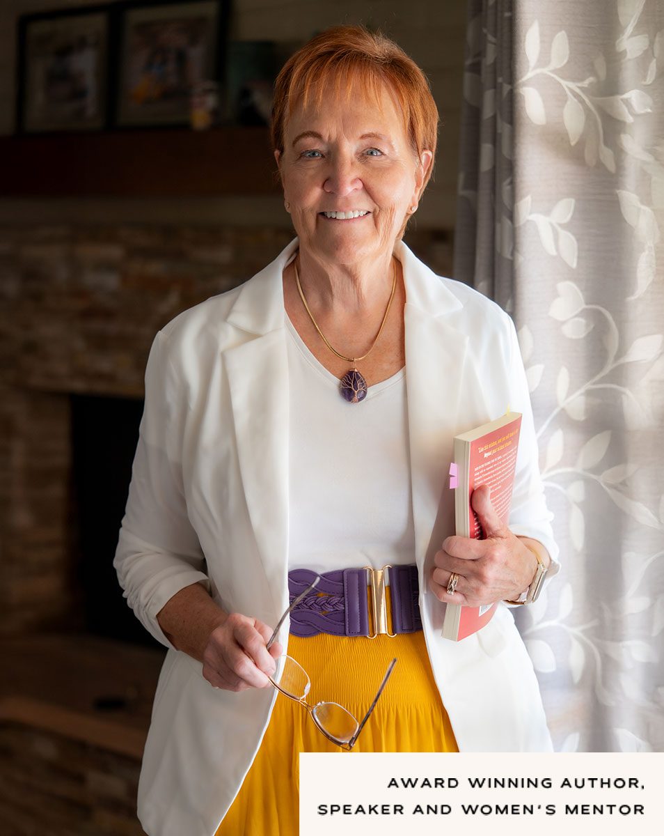 Linda posing with her book in a white jacket